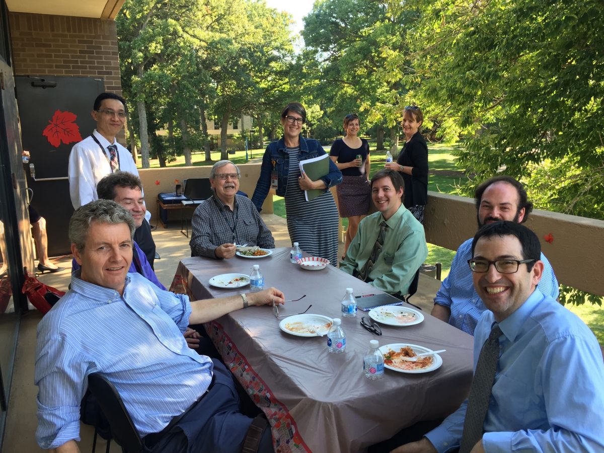 10 FET members sitting at a table and standing outdoors eating